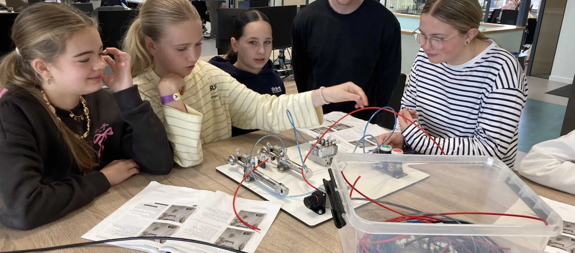 Meiden werken samen aan elektronische apparaten in een moderne werkruimte tijdens Girls Day.