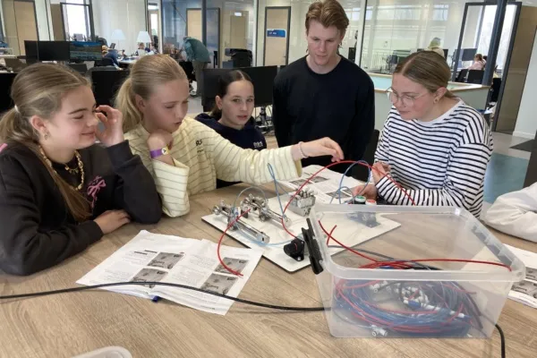 Meiden werken samen aan elektronische apparaten in een moderne werkruimte tijdens Girls Day.